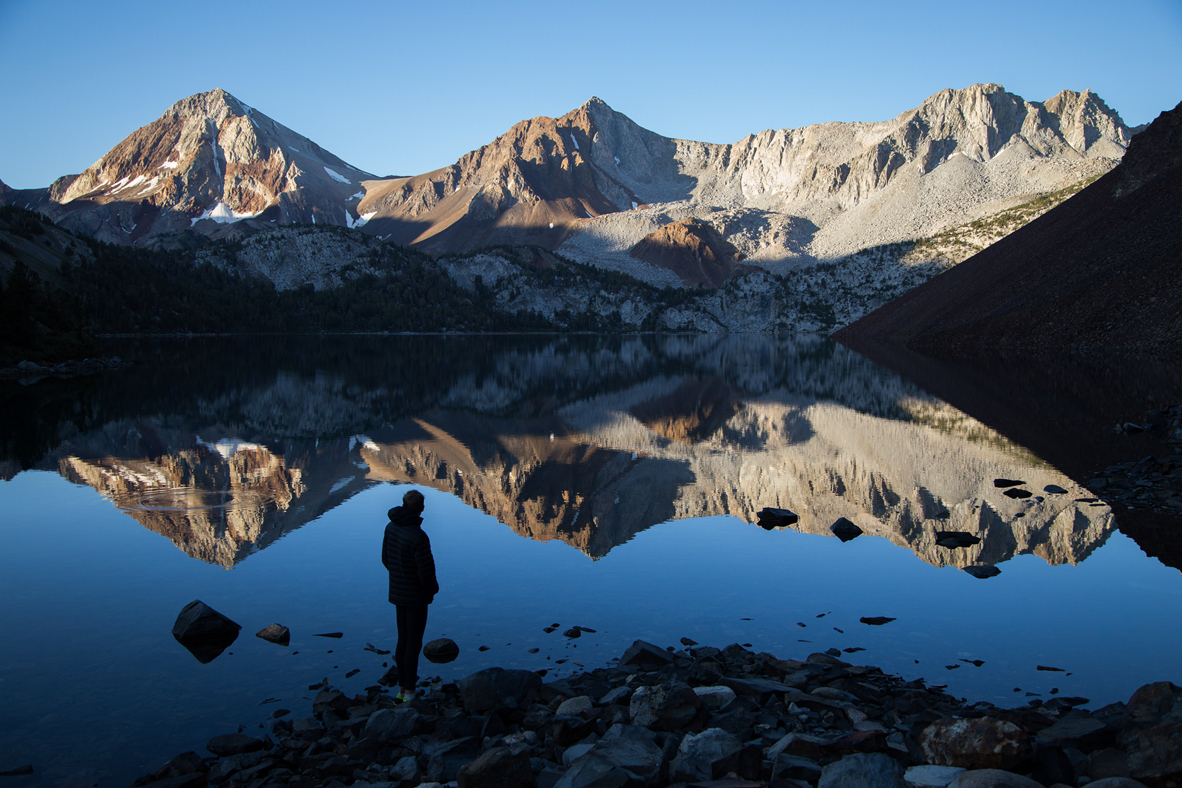 A person admires sunrise on the mountain peaks at Lake Dorothy in Mammoth Lakes, California