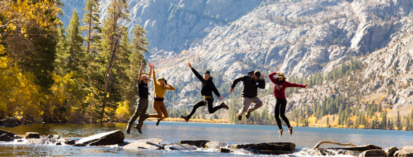 Five people jump up from rocks across Silver Lake in June Lake, California
